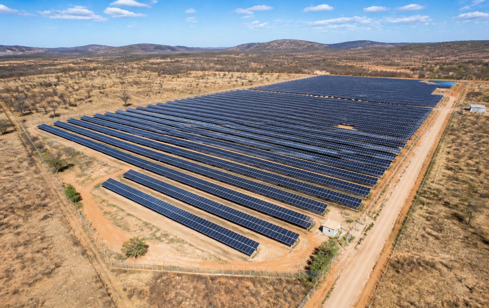 Vista aérea de uma usina solar com longas fileiras de módulos fotovoltaicos